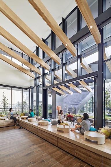 A group of people sitting in a room with a wood floor and glass ceiling.